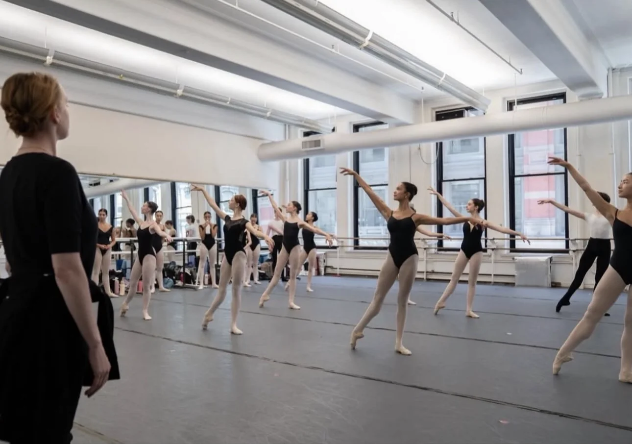 Ballet students practicing a center combination as a teacher observes